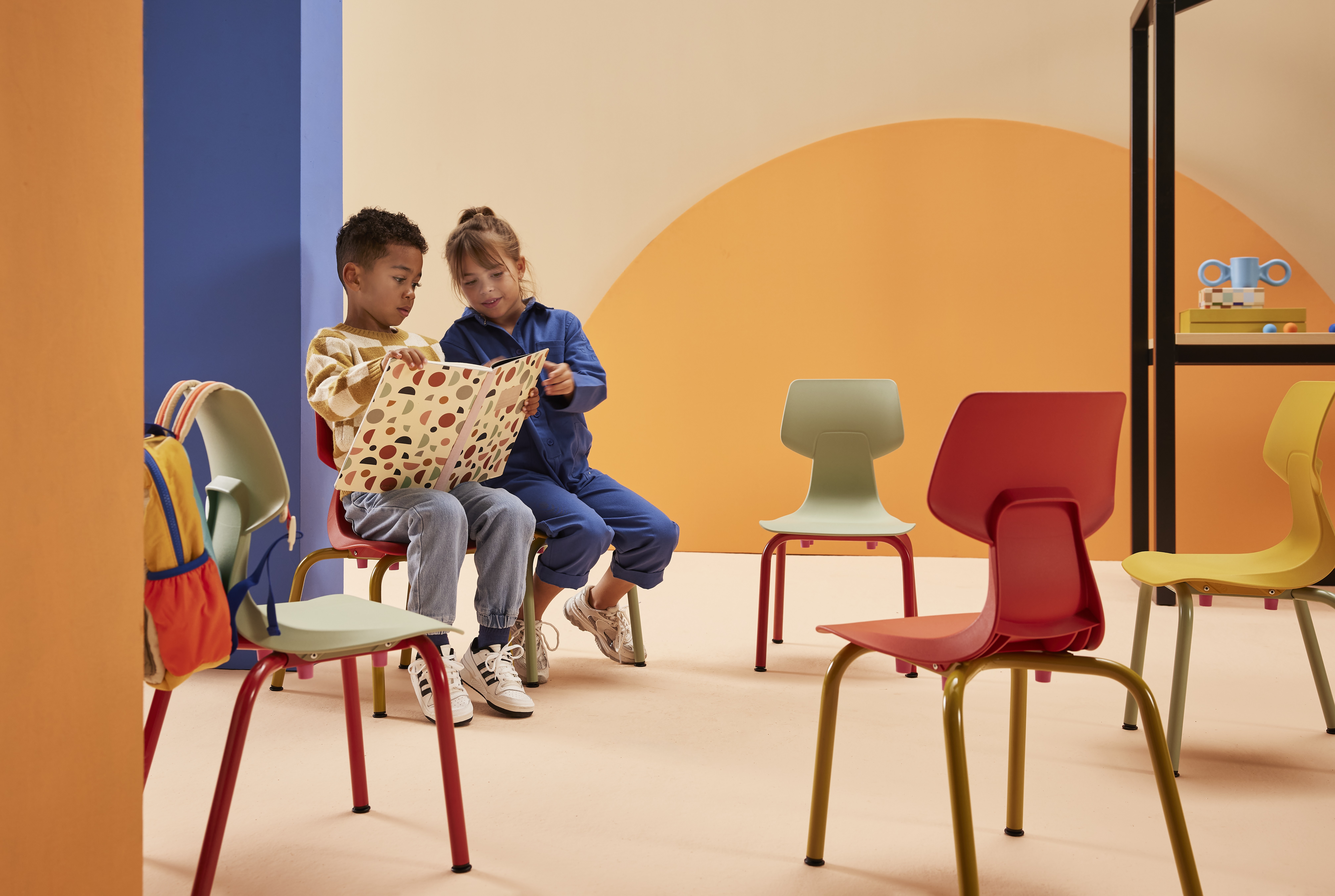 Gispen WIZZ 4 leg frame in yellow chairs with a blue cantilever chair and models reading in a blue pink primary education setting front view