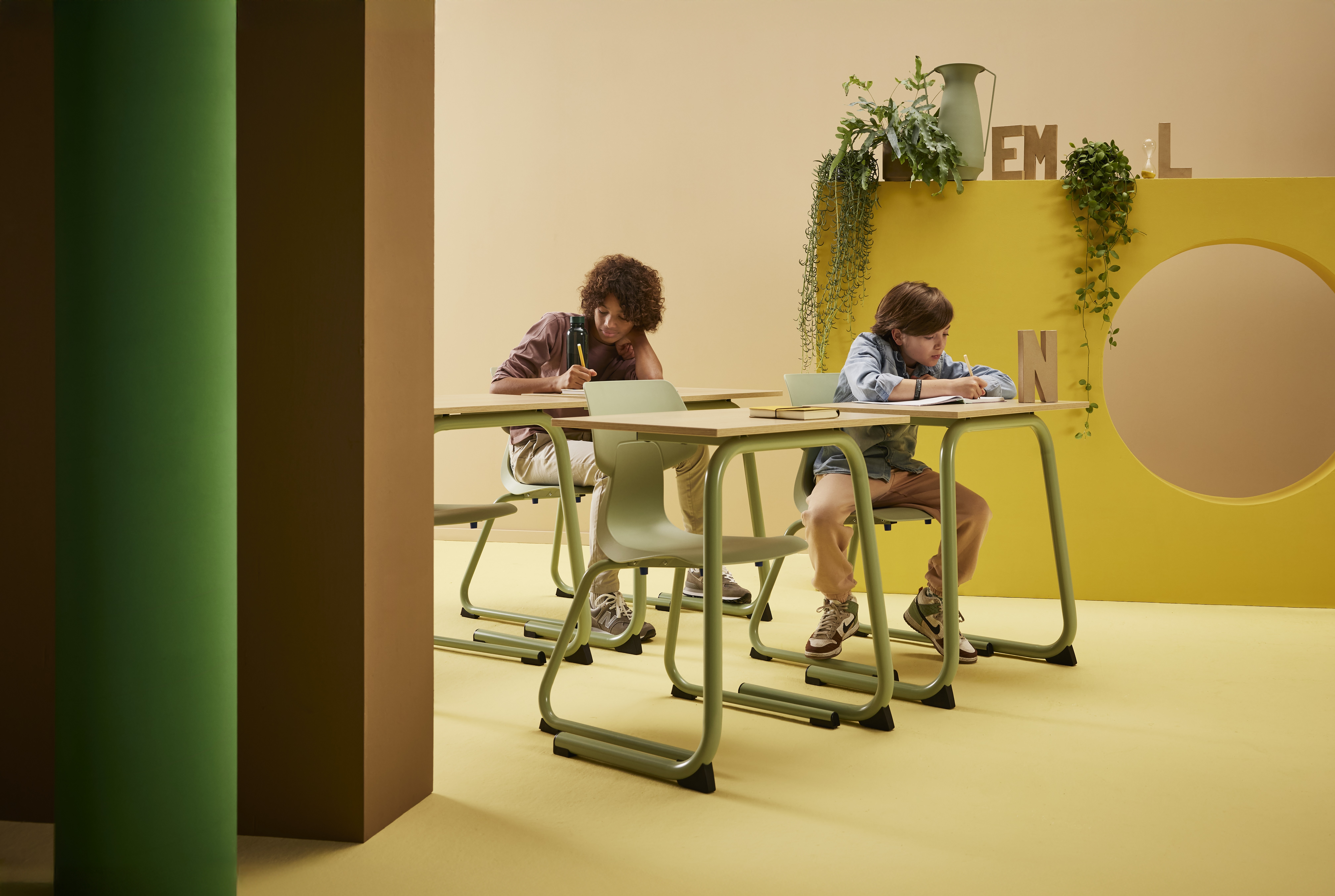 Gispen WIZZ c frame in green chairs with EDUU comfort tables with male models in a yellow green secondary education setting front left view